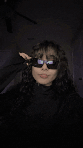a girl wearing sunglasses and a black shirt smiles for the camera
