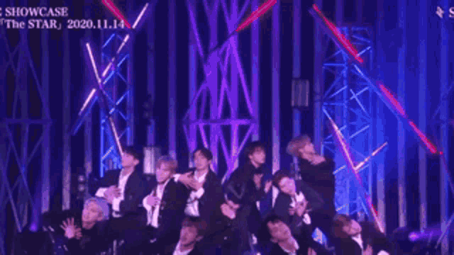 a group of men are dancing on a stage and one of them is wearing a choker around his neck .