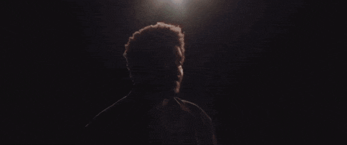 a man with a beard is standing in a dark room looking up