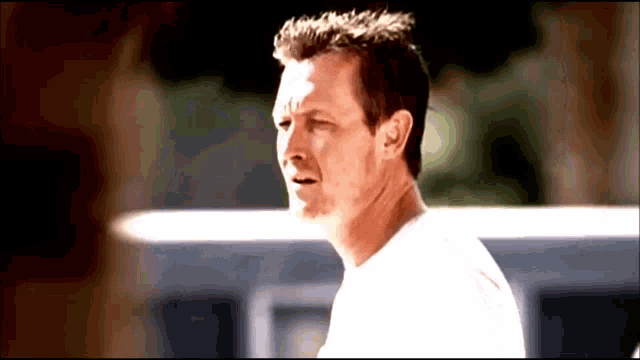 a man in a white shirt is looking at something in the distance