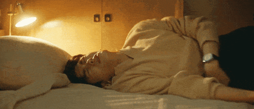 a man laying on a bed with his eyes closed