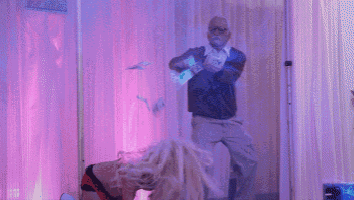 a man is holding a bunch of money while a woman performs on a pole