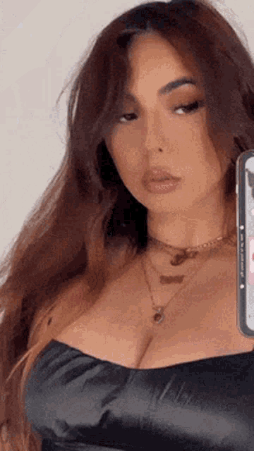 a woman in a black top is taking a selfie with her phone