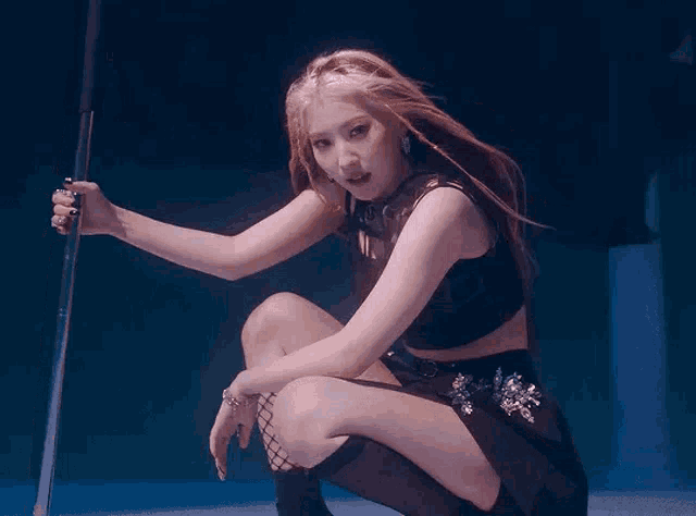 a woman is kneeling down with her legs crossed and holding a pole in her hand .
