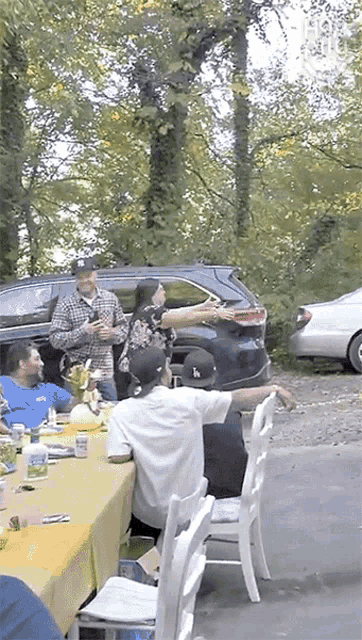 a group of people are sitting around a table with a man holding a watermelon