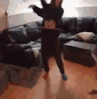 a child is doing a handstand in front of a couch .