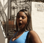a woman in a blue tank top is standing in front of a sign that says " comca casa "
