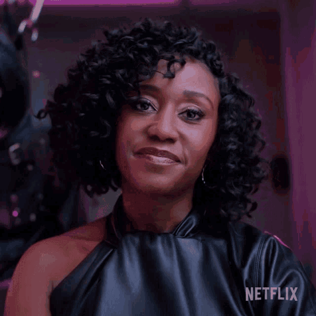 a woman with curly hair is smiling in front of a purple background with netflix written on it