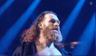 a man in a black hoodie is standing on a stage in front of a sign that says wwe .