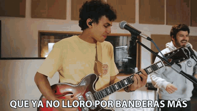 a man playing a guitar in front of a microphone with que ya no lloro por banderas mas written below him