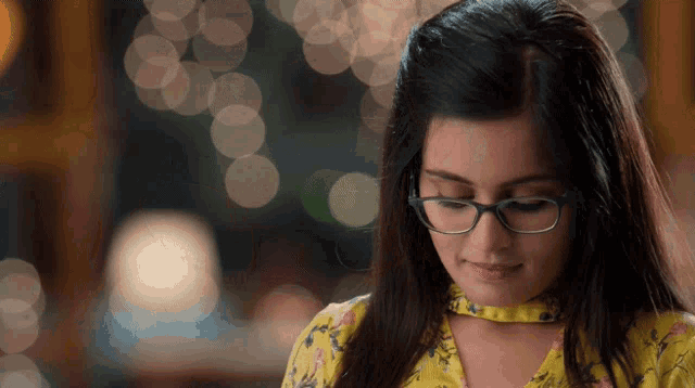 a girl wearing glasses and a yellow shirt is smiling