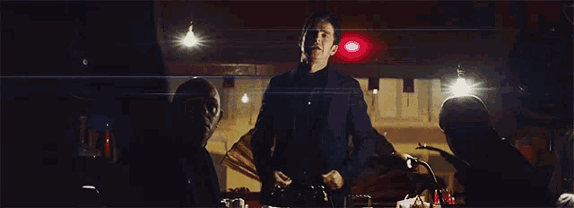 a man in a black suit stands in a dark room