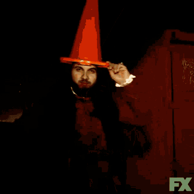 a man wearing an orange cone with the words we drank the blood of some people below him
