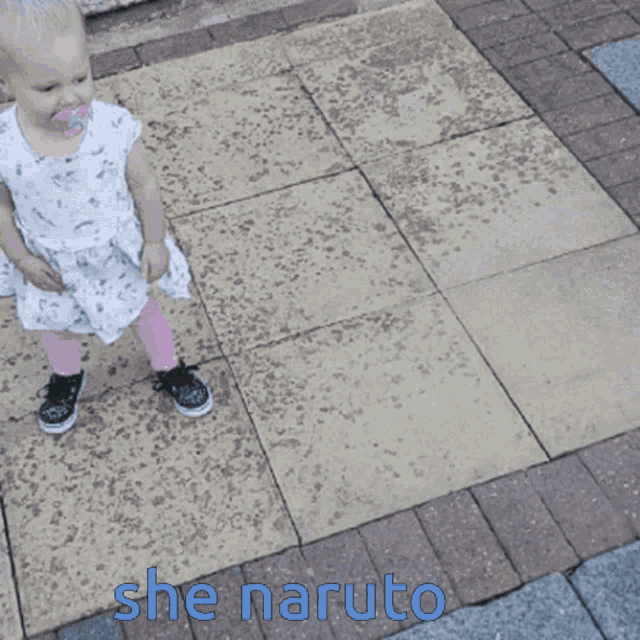 a baby in a white dress and pink socks is walking on a brick sidewalk with the words she naruto written below her