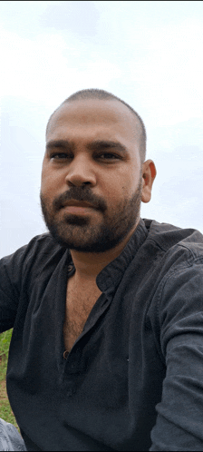a man with a beard wearing a black shirt is taking a selfie