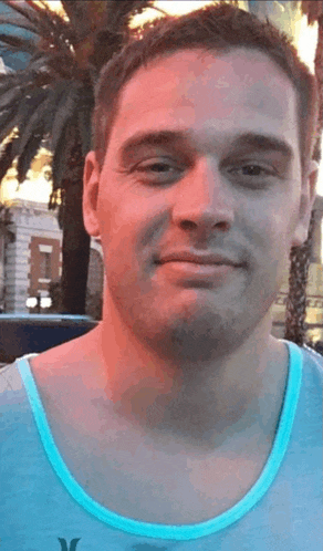a man wearing a blue tank top with the letter x on it