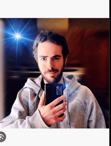 a man in a grey hoodie takes a selfie with his cell phone