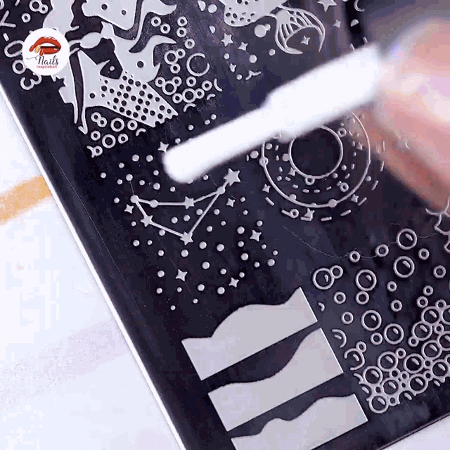 a person is stamping a design on a nail plate with nails written on the bottom