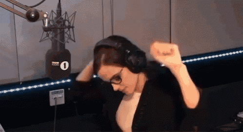 a woman wearing headphones is dancing in front of a microphone with the number 1 on it .