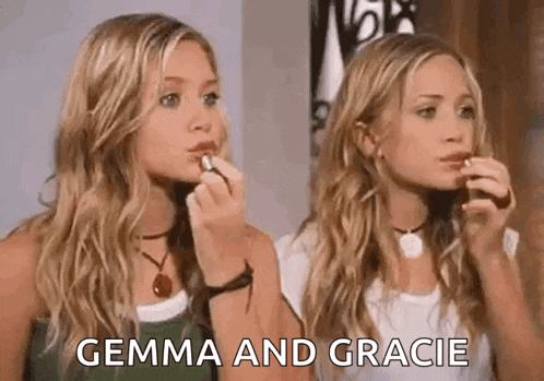 two blonde women are applying lipstick to each other .