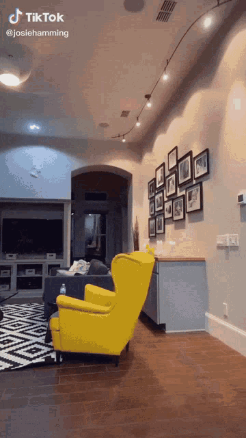 a living room with a yellow chair and a wall of pictures