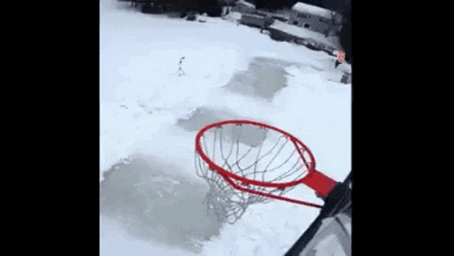 a person is playing basketball in the snow and a basketball hoop is in the snow .