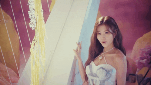 a woman in a white dress is standing next to a wall