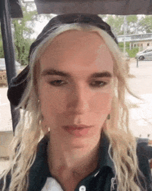 a close up of a person 's face with blonde hair and a hat