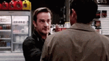 two men are standing next to each other in a store and talking .