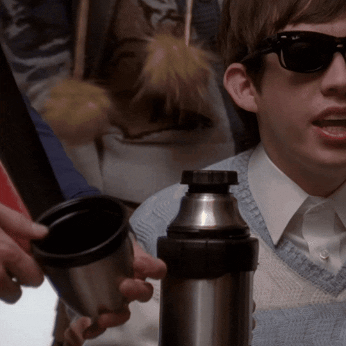 a boy wearing sunglasses is holding a thermos in his hand