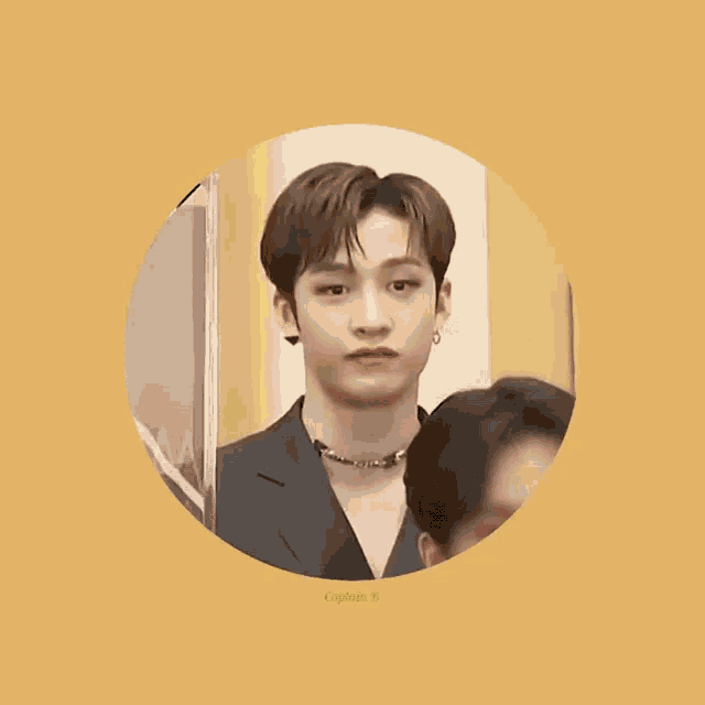 a young man wearing a suit and a necklace is standing in a circle on a yellow background .