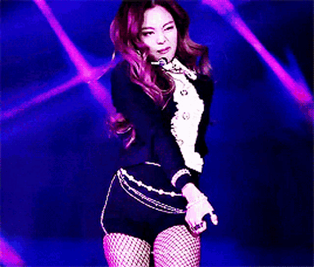 a woman in fishnet stockings and a black jacket is dancing on a stage .