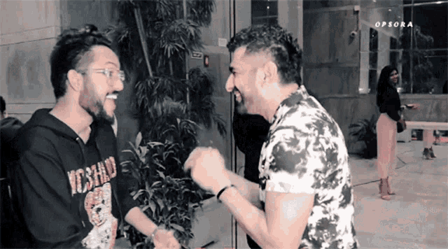 two men are laughing and one has a moschino sweatshirt on