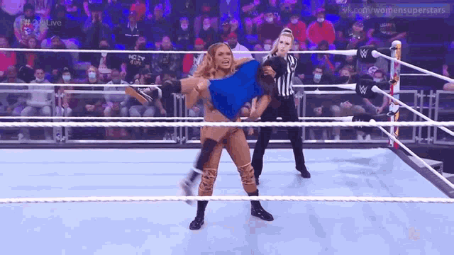 a woman is wrestling in a wrestling ring with a referee .
