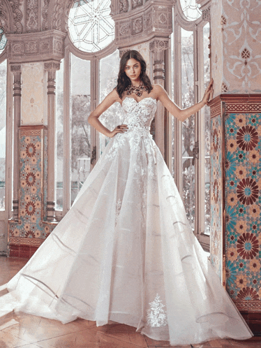 a woman in a white ball gown is standing in front of a window
