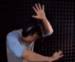 a man wearing headphones is doing a dab with his hands in the air .