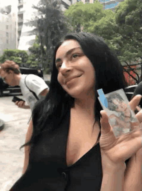 a woman in a black dress is holding a picture of a man in a white shirt