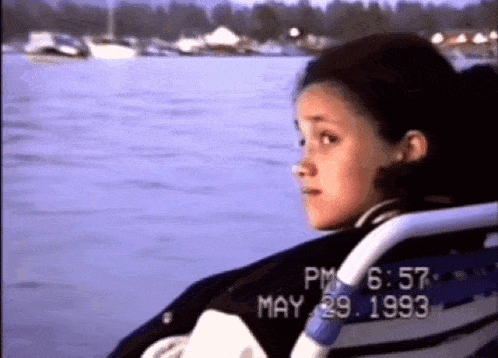 a girl sits in a chair looking out over a body of water with the date may 29 1993