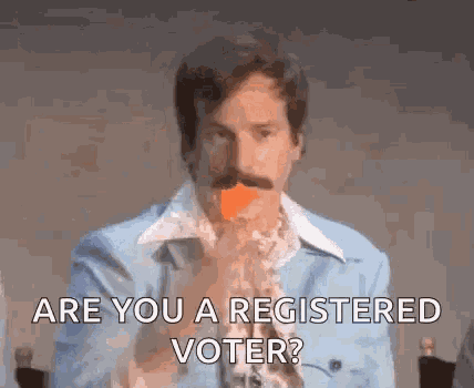 a man with a mustache is holding a carrot in his mouth and asking if he is registered to vote .