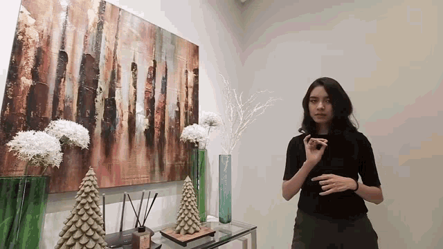 a woman is standing in front of a painting on the wall