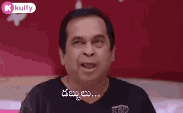 a man in a black shirt is making a funny face and pointing at something .