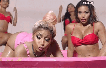 a group of women in bikinis are laying in a pink pool .