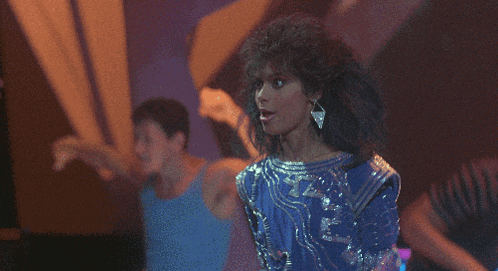 a woman in a blue dress is dancing in front of a crowd