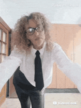 a woman with curly hair wearing glasses and a white shirt with a black tie