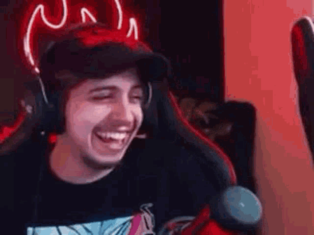 a man wearing headphones and a hat is sitting in a chair and laughing .