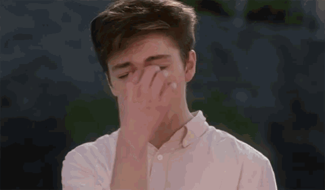 a young man in a pink shirt is making a face