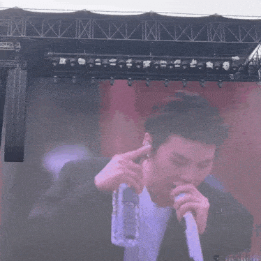 a man is holding a bottle of water in front of a microphone on a stage