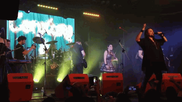 a group of people playing instruments on a stage with a large screen behind them that says ' nirvana ' on it