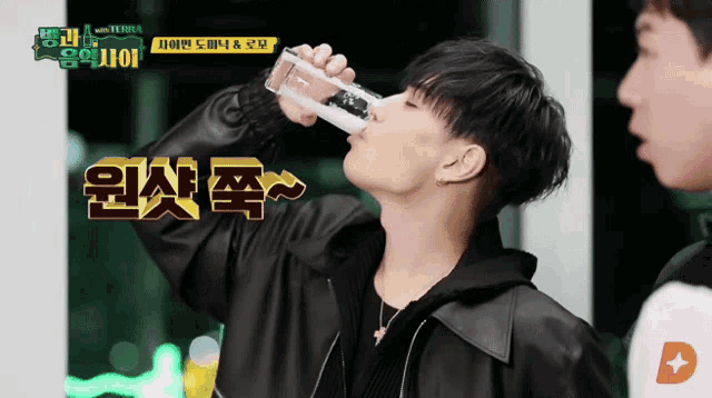 a man is drinking from a glass with korean writing on the bottom
