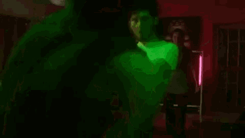 a group of people are dancing together in a dark room with green lights .
